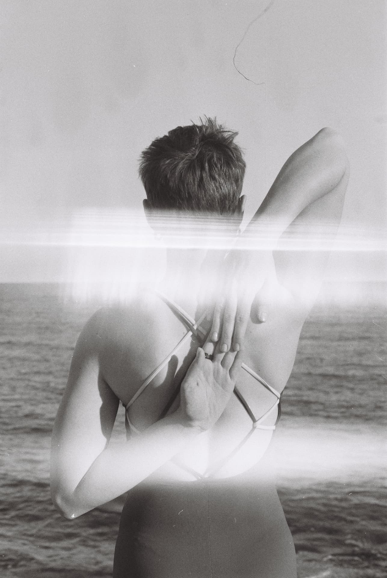 Black and white portrait by the sea, arms behind the back